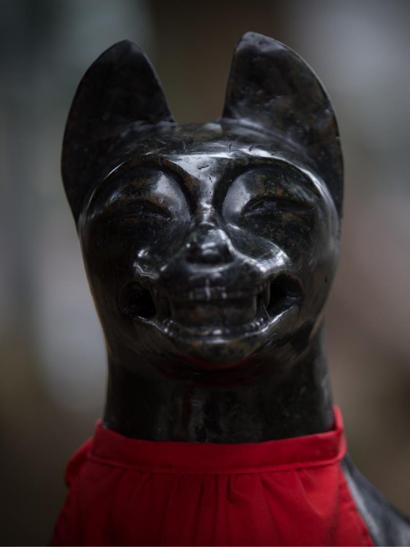 歯を見せて笑っているような表情の黒い狐の石像